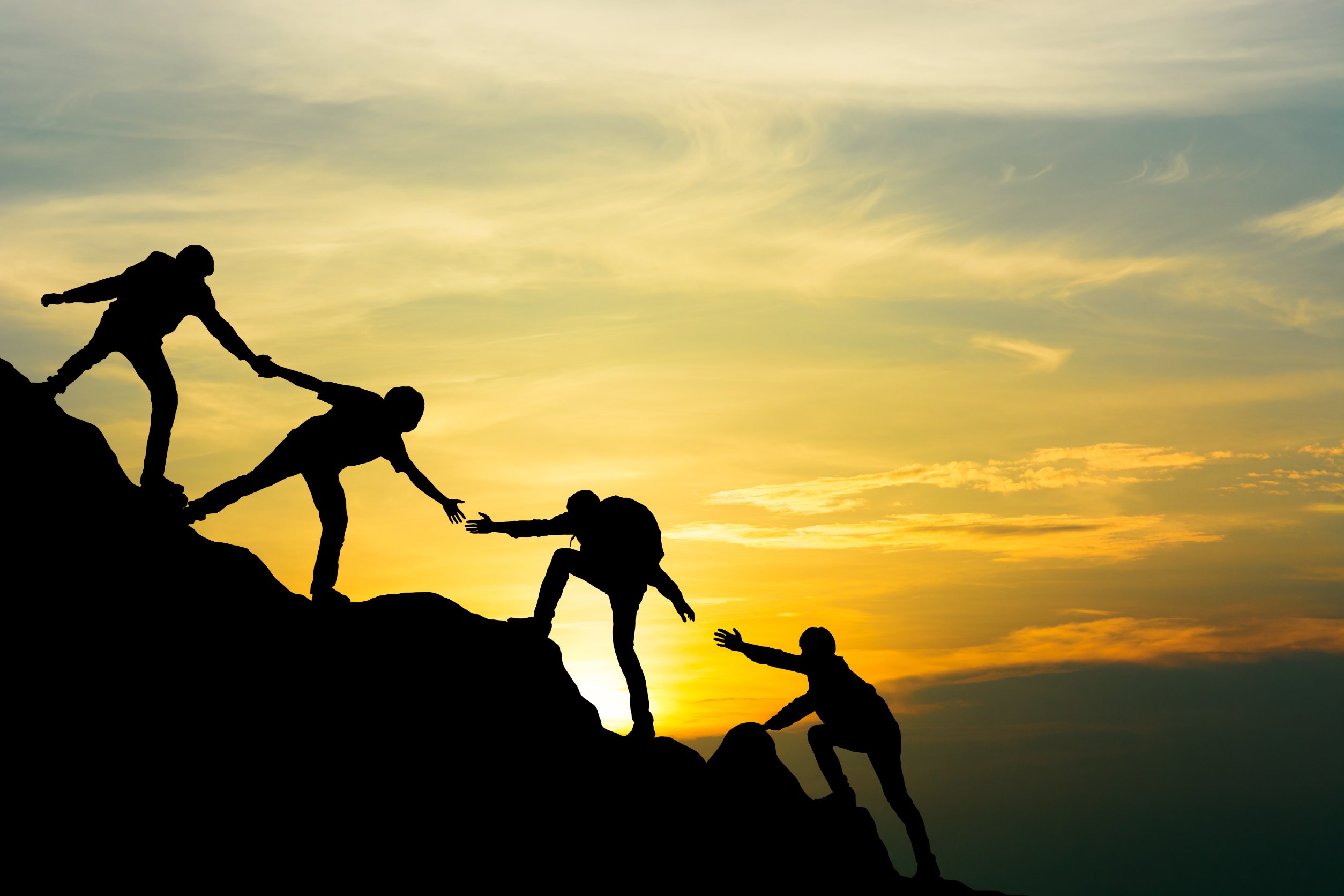 112725847_m Group of people on peak mountain climbing helping team work with sunset background , travel trekking success business concept